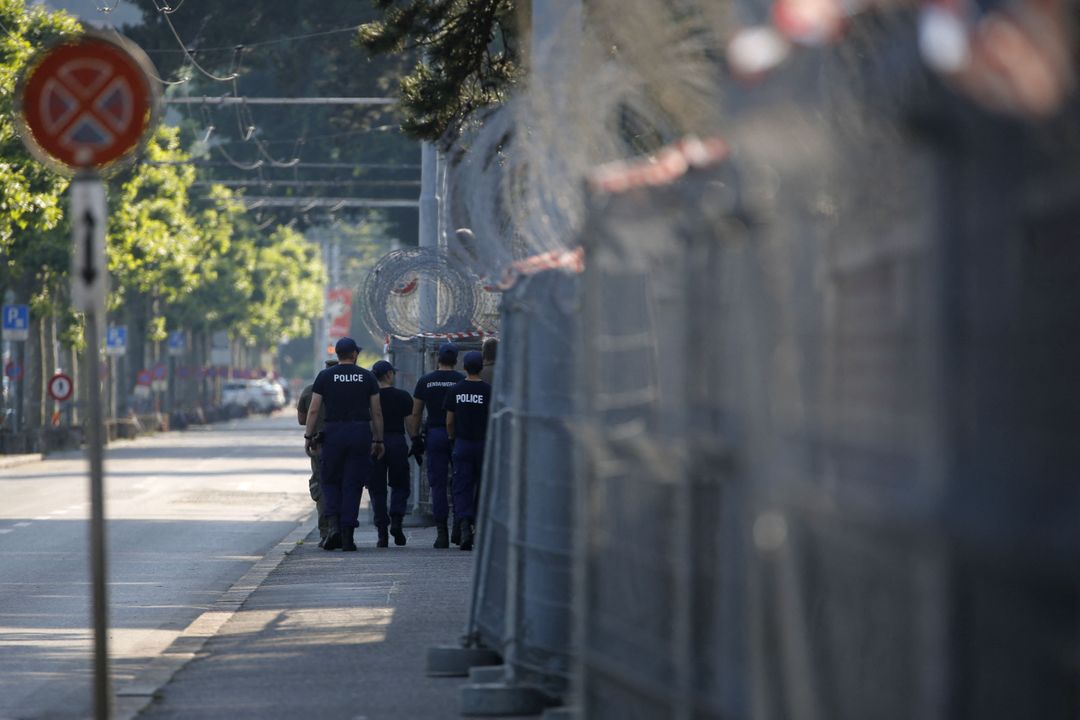 Poliiseja kävelee kadulla, reunassa aitaa ja sen päällä piikkilankaa.
