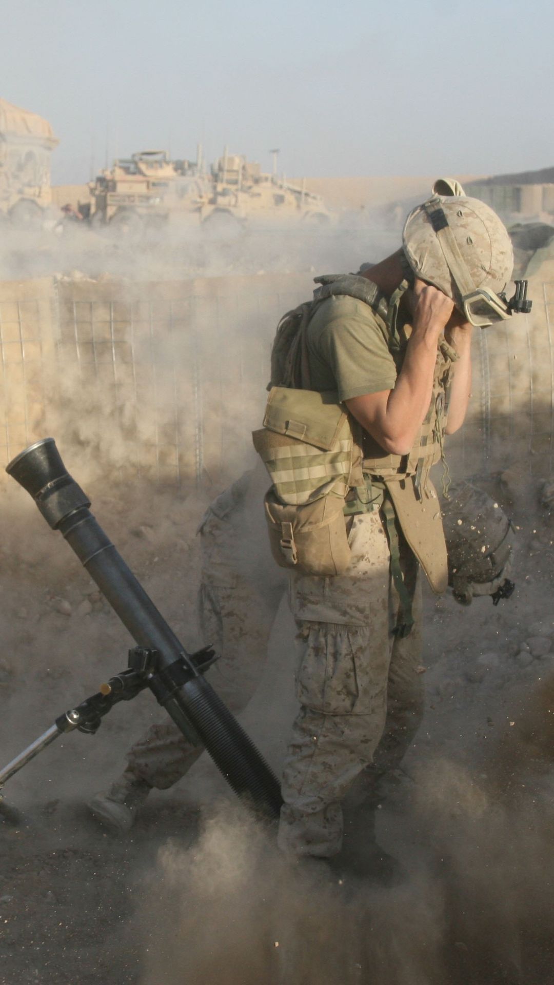 Sotilas pitelee korviaan pölypilven keskellä, vieressä raketinheitin. 