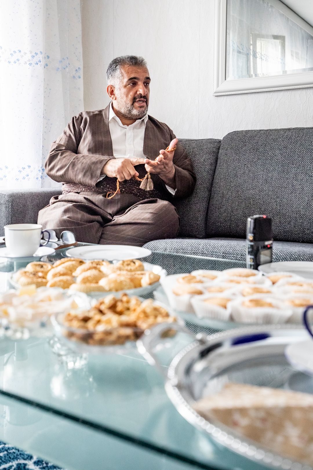 Saber Sorani istuu sohvalla ja puhuu. Pöydällä on keksejä.