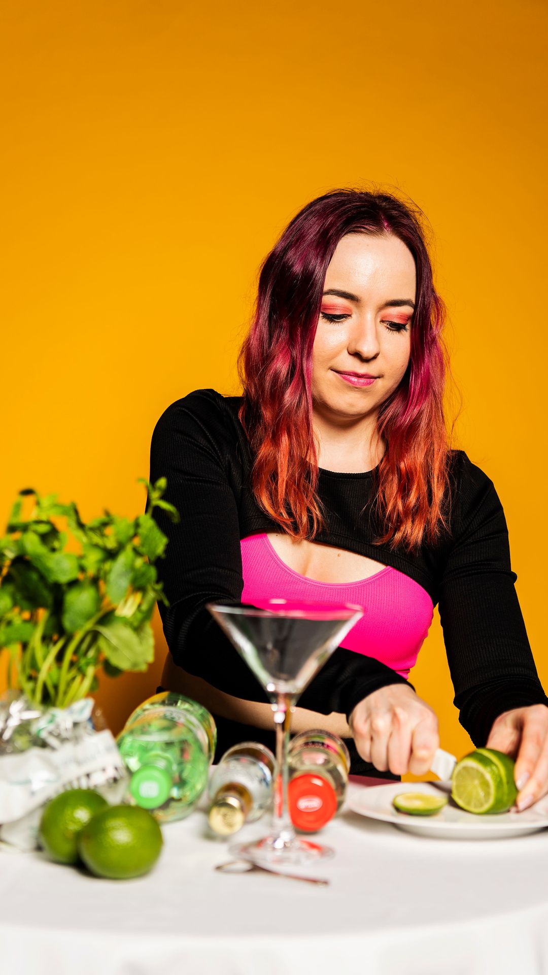 Wilma Tuominen leikkaa veitsellä siivuja limestä. Pöydällä on ainekset alkoholitonta drinkkiä varten.