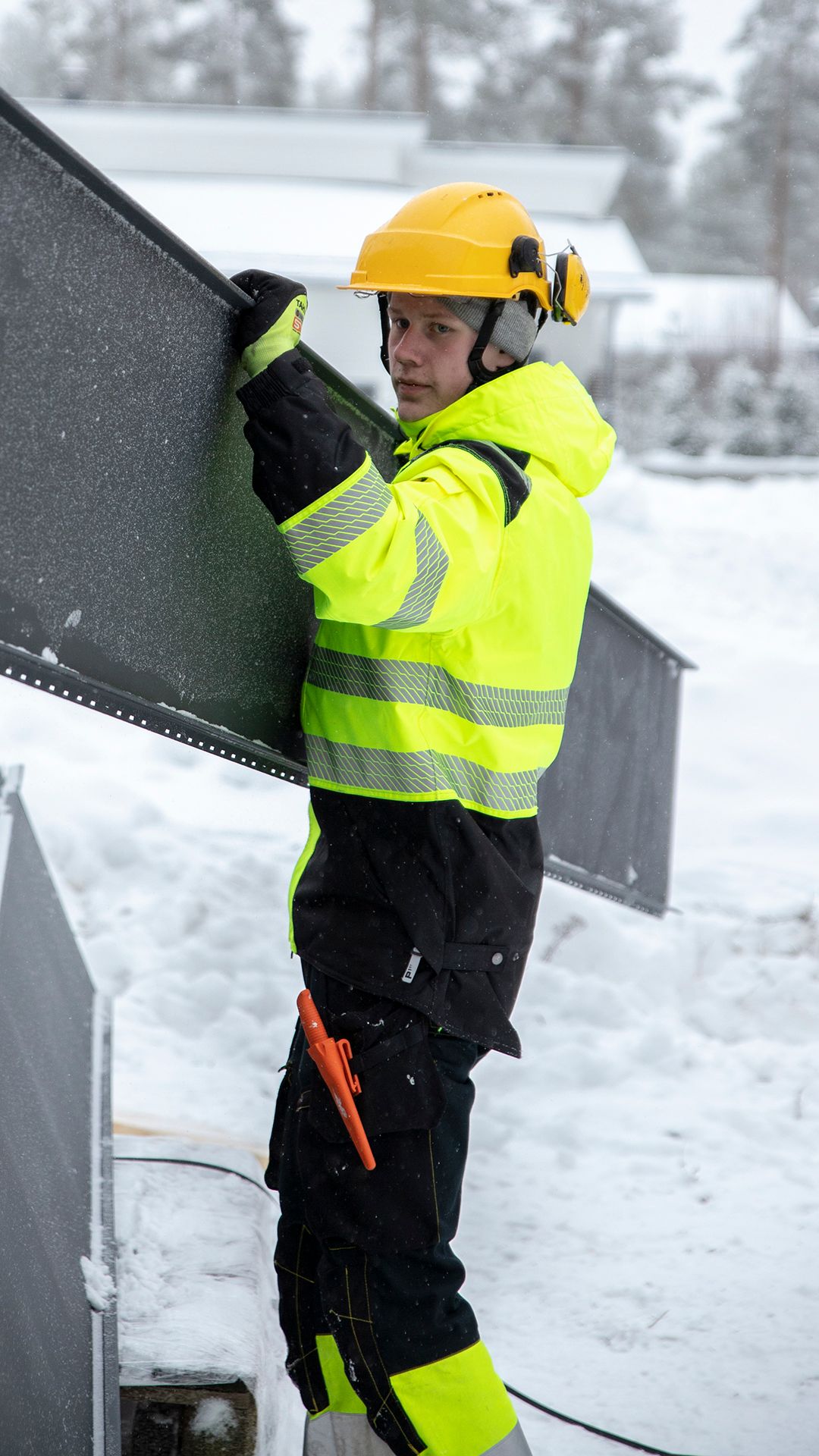 Niilo Rinta-Tassi kantaa kattopeltiä rakennustyömaalla