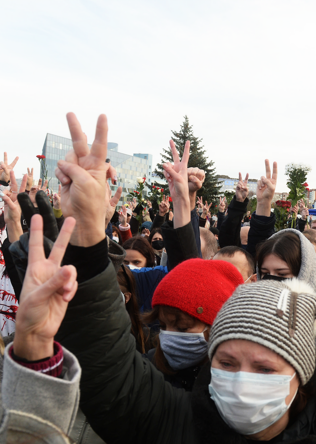 Lukuisat sormet osoittavat voitonmerkkiä ilmassa.