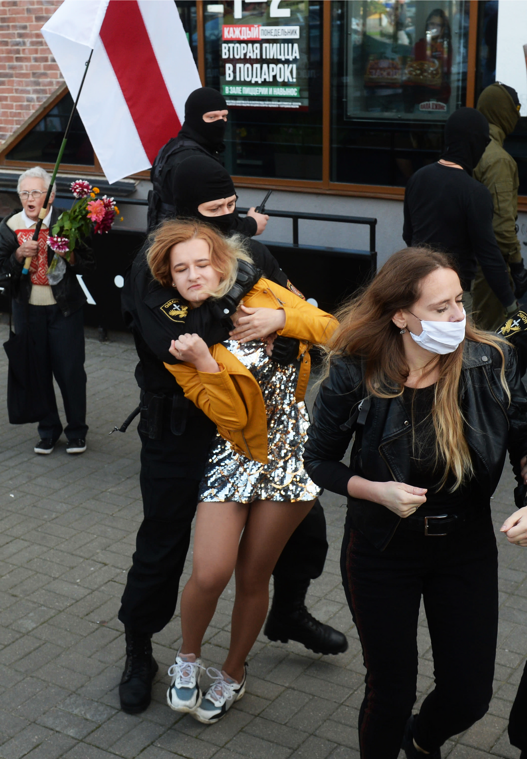 Poliisi retuuttaa nuorta naista.