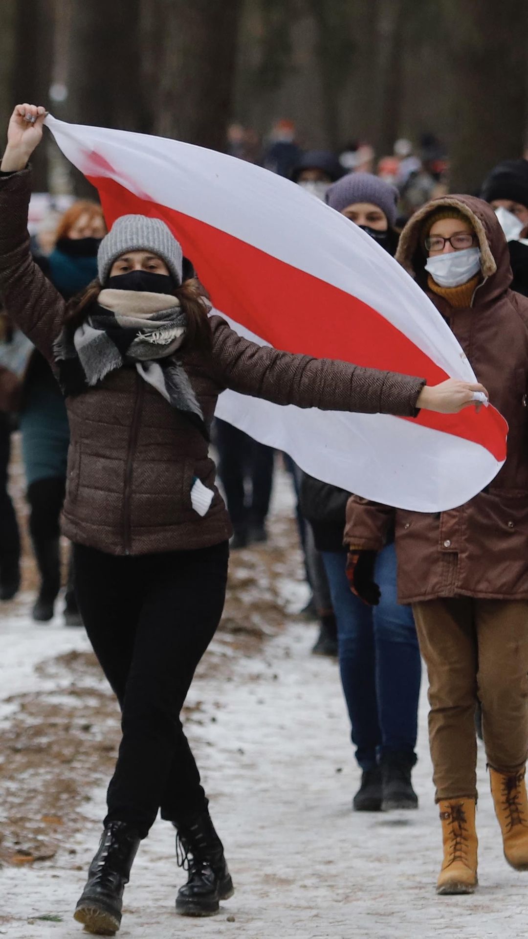 Joukko osoittaa mieltään talvella Valko-Venäjän lipun kanssa.